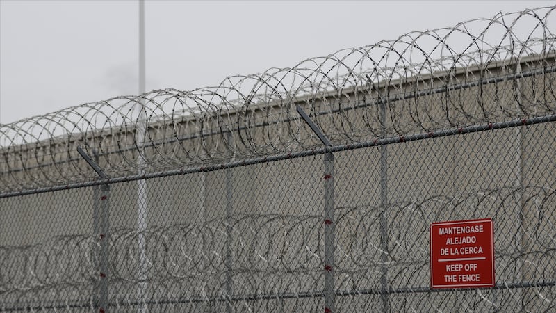 FILE - Barbed wire fencing is shown behind a sign in English and Spanish in a recreation yard...