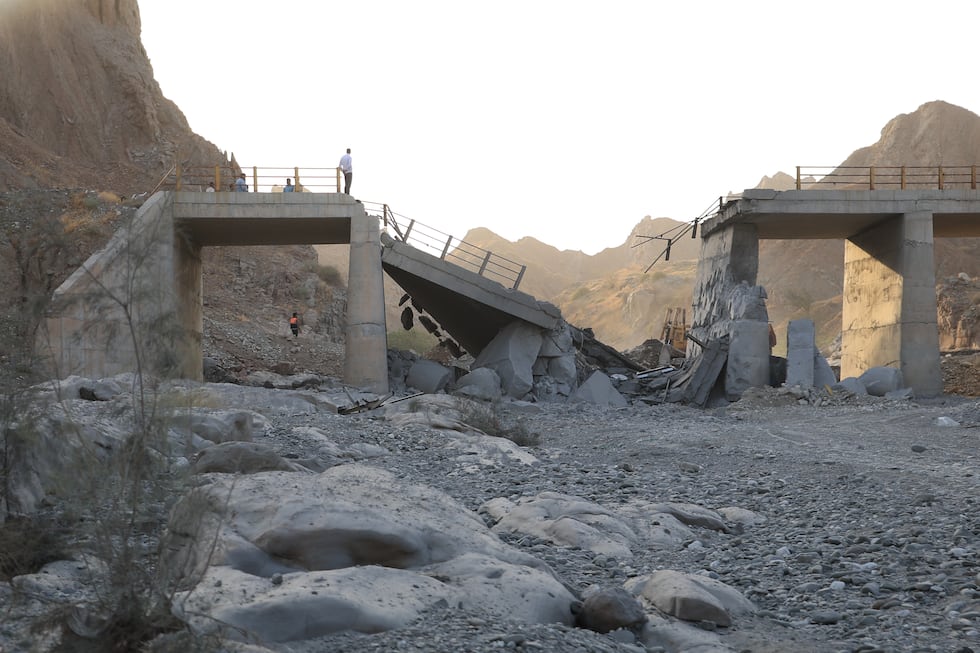 People stand on a bridge destroyed after a strike in Hormozgan province, southern Iran,...